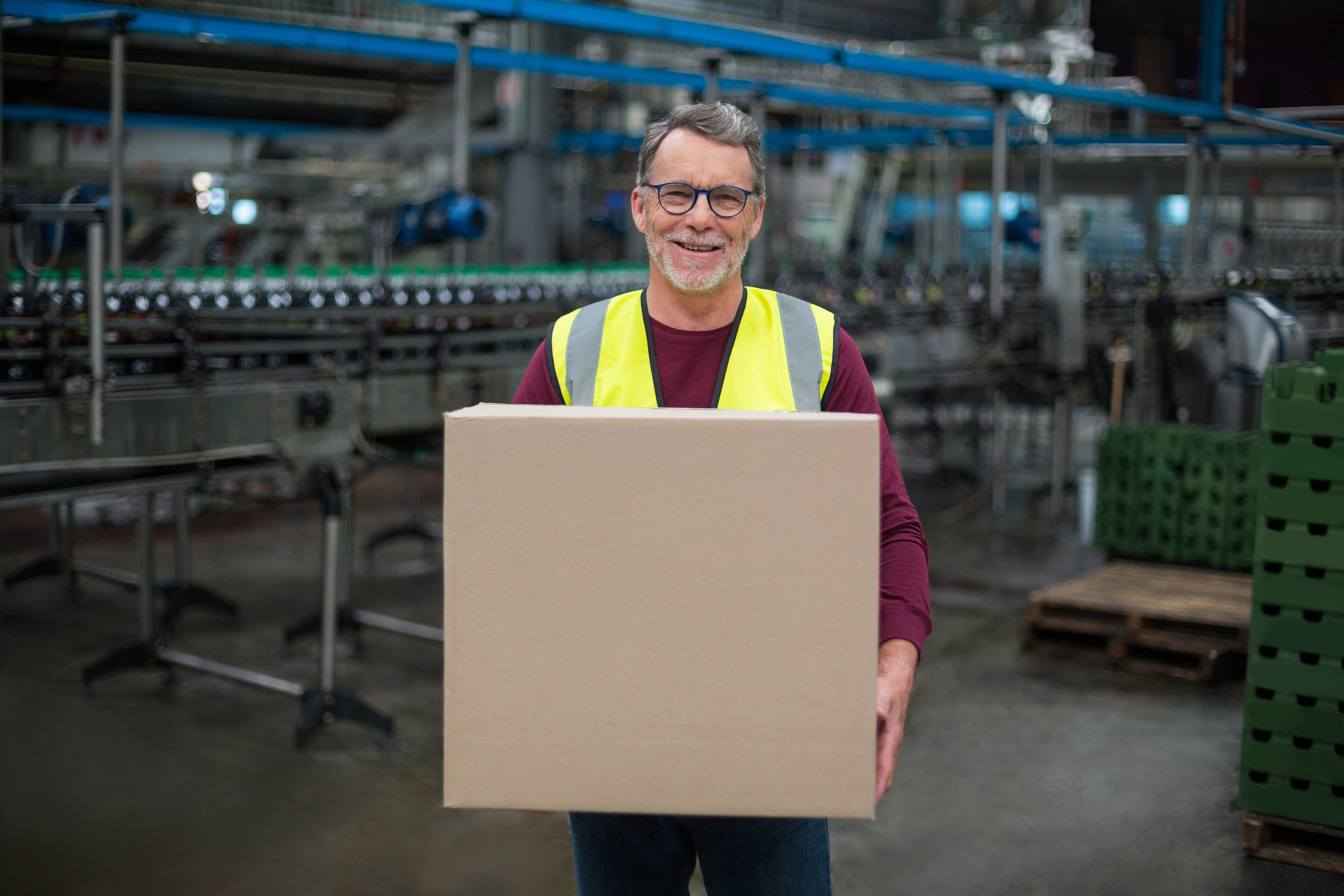 Portrait of factory worker holding cardboard box in drinks production factory